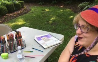 smiling young adult with red hat and art supplies