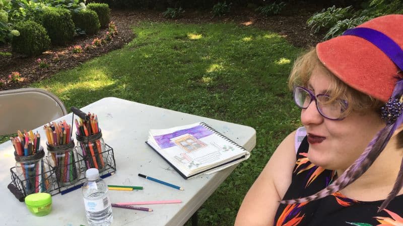 smiling young adult with red hat and art supplies