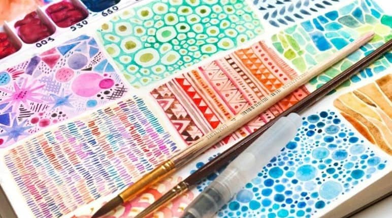 Small rectangles with colorful watercolor patterns and three paint brushes