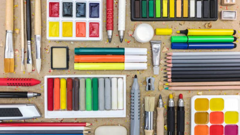 Very colorful drawing and painting art supplies neatly arranged on desk