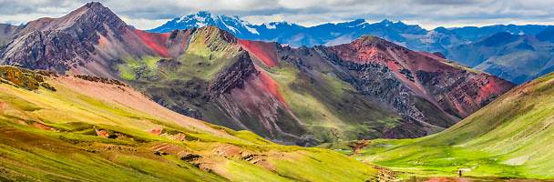 vinicuna=rainbow mountains peru very colorful mountain range with yellows, pinks, greens and blues against a blue sky.