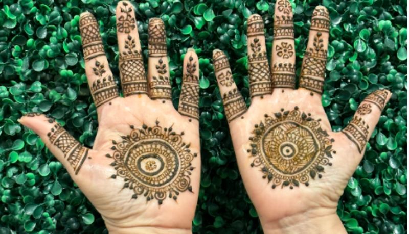 hands palms up with henna mandalas painted on them
